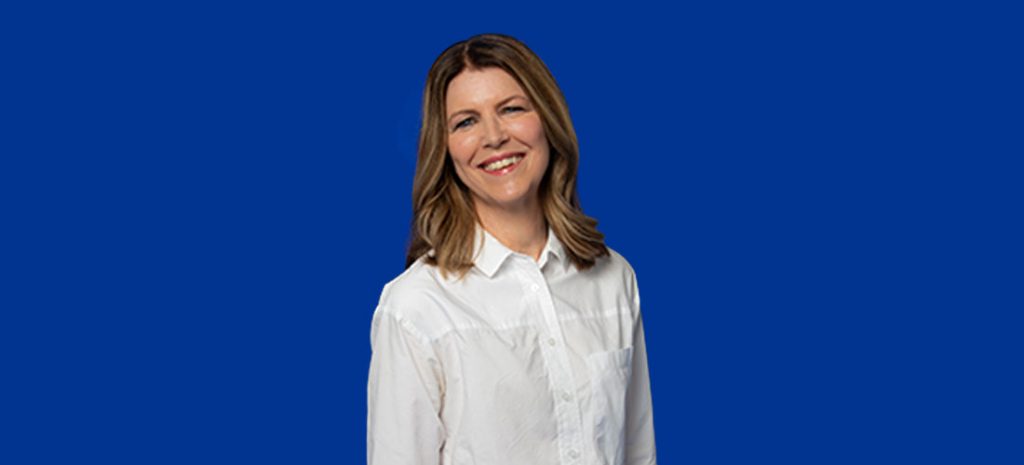 Image of middle aged lady in a white shirt smiling at the camera