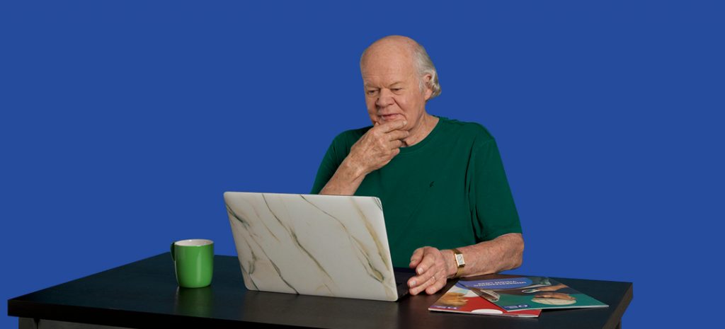 Senior man at a laptop with a coffee cup