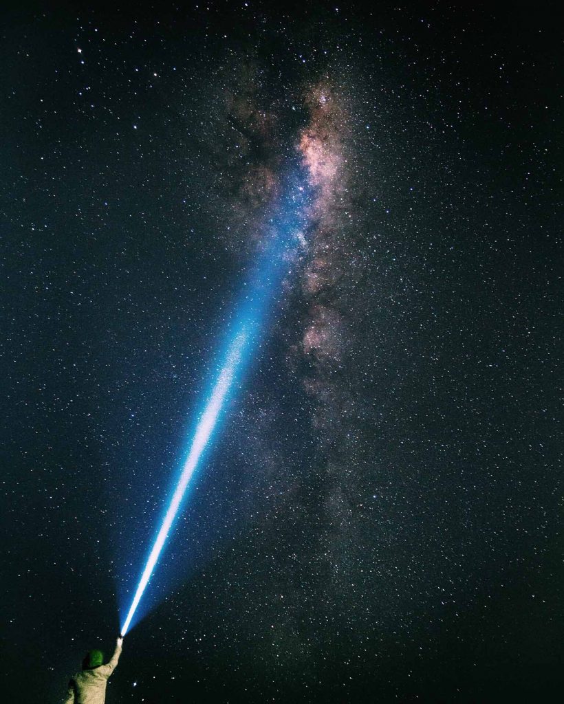 Image shows a person pointing a torch into the sky with the Milky Way visible in the background. Photo: Floyd Mallon